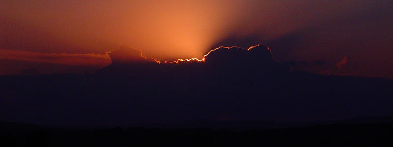 sun breaking through from behind a cloud at sunrise